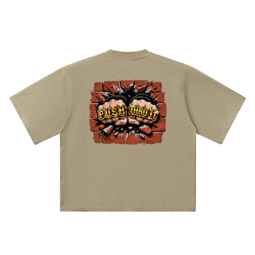 A beige short-sleeve t-shirt shown from the back, featuring a large graphic print of two clenched fists bursting through a brick wall with the words 'PUSH THRU IT' in yellow.