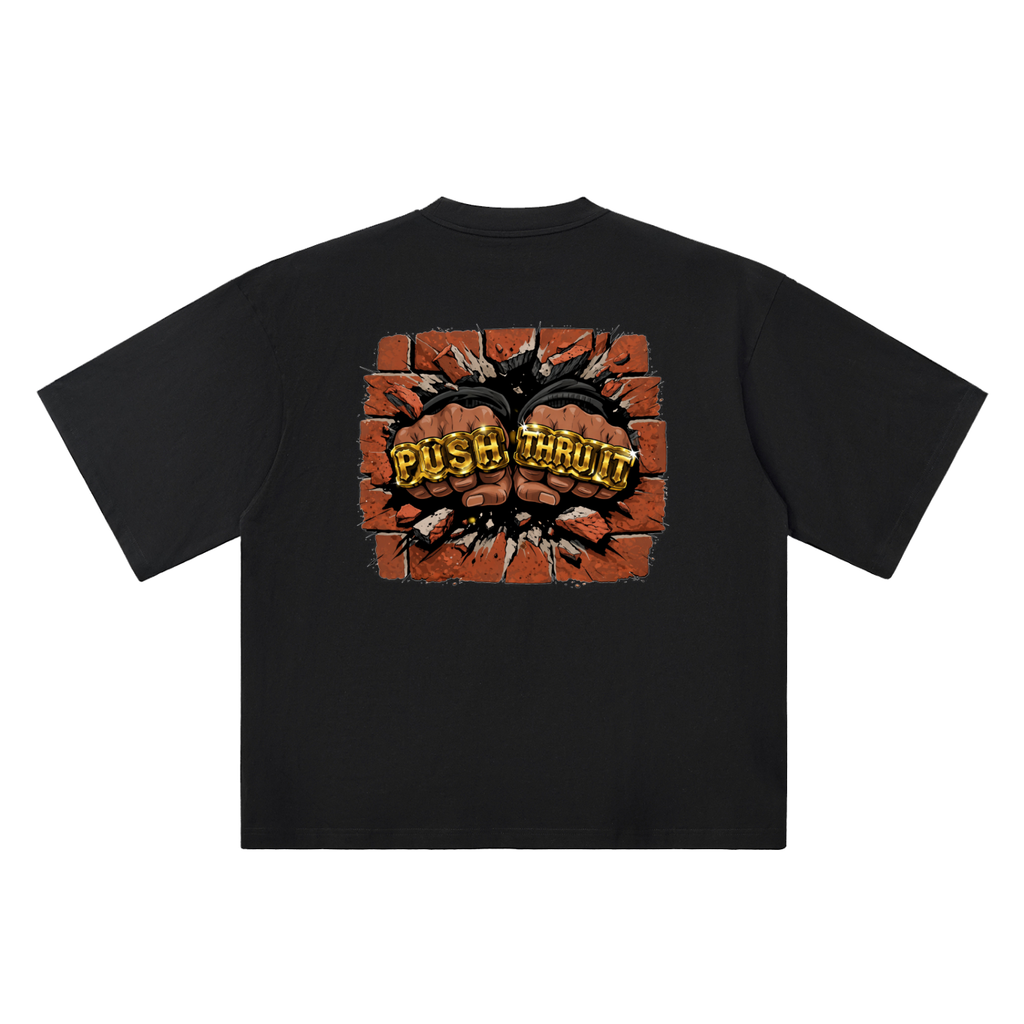 A black short-sleeve t-shirt shown flat against a white background, featuring a large graphic print on the back with two fists bursting through a brick wall and the words 'PUSH THRU IT' in gold fist cuffs.